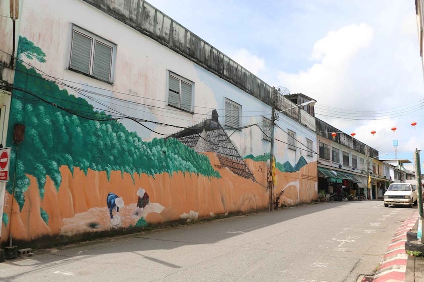 A street with a mural on a building, a no entry sign, and a parked car. 3