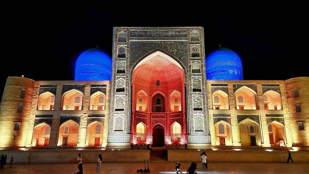 A large, illuminated building with two domes and intricate architectural details. 5