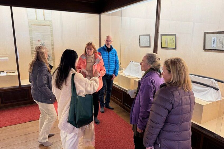 A group of people in a museum-like setting with glass display cases and informational plaques. 5