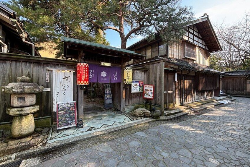 A traditional Japanese building with wooden architecture, stone paving, and signage. 2