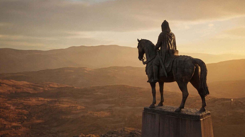 A statue of a person on horseback on a pedestal, overlooking a mountainous landscape during sunset. 2
