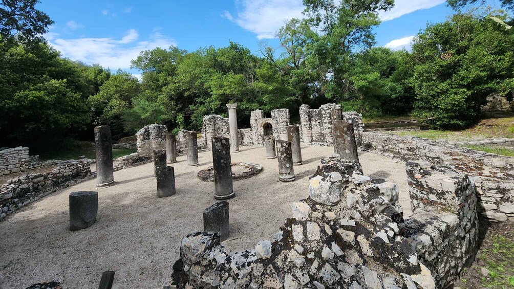 Ancient ruins with stone columns and walls, surrounded by lush greenery. 2