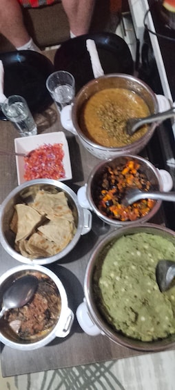 A table with various dishes including a green sauce, a brown soup, a red salsa, and a white dish with a spoon. 3