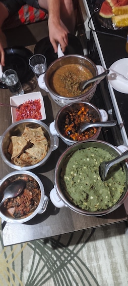 A variety of dishes including a green dip, a red vegetable mix, and a brown stew. 2