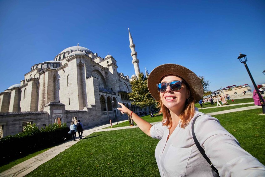 A woman pointing at a historic building with domes and a minaret. 5