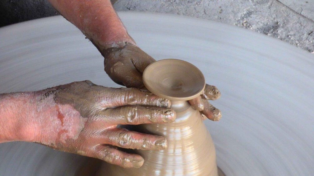 A person shaping a clay pot on a pottery wheel. 4