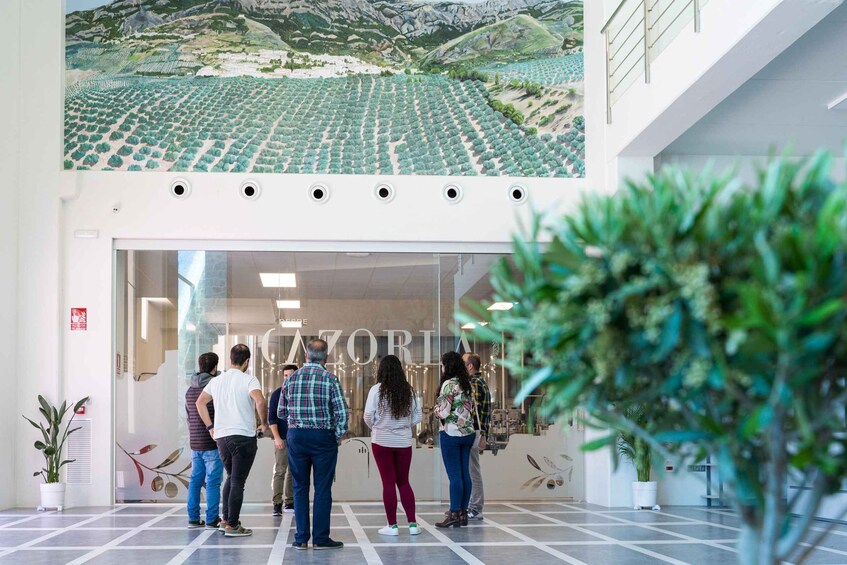 A group of people standing in front of a building with a large mural of a landscape. 4