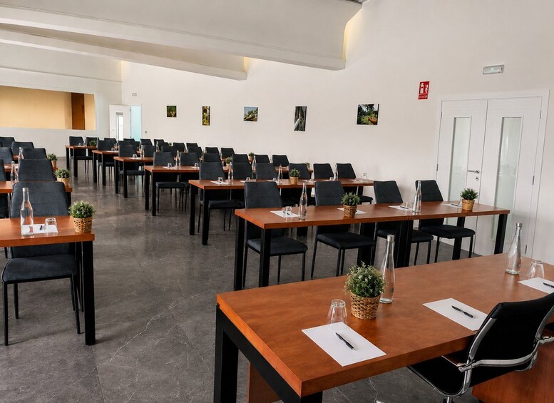 A conference room with multiple tables and chairs, some with plants and water bottles. 5