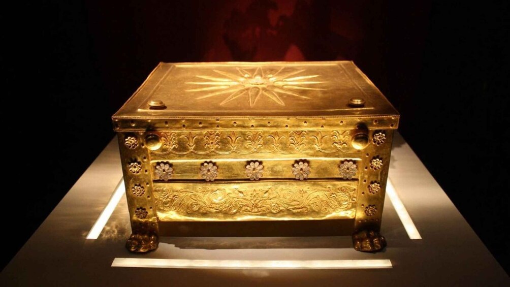A golden chest with intricate floral engravings and a central sun-like design. 1