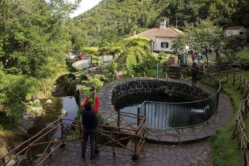 A stone bridge over a stream, a circular stone structure, and a house in the background. 4