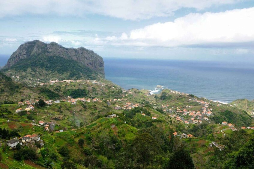 A coastal village with houses on green hills and a mountain in the background. 3