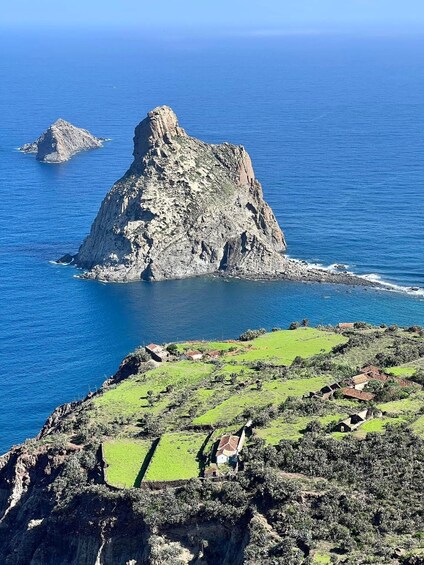 A coastal landscape with a prominent rocky outcrop surrounded by the sea. 4