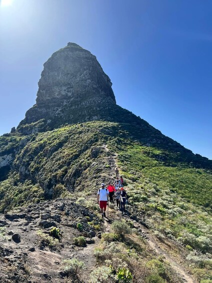 A group hiking on a rocky trail towards a prominent mountain peak. 2
