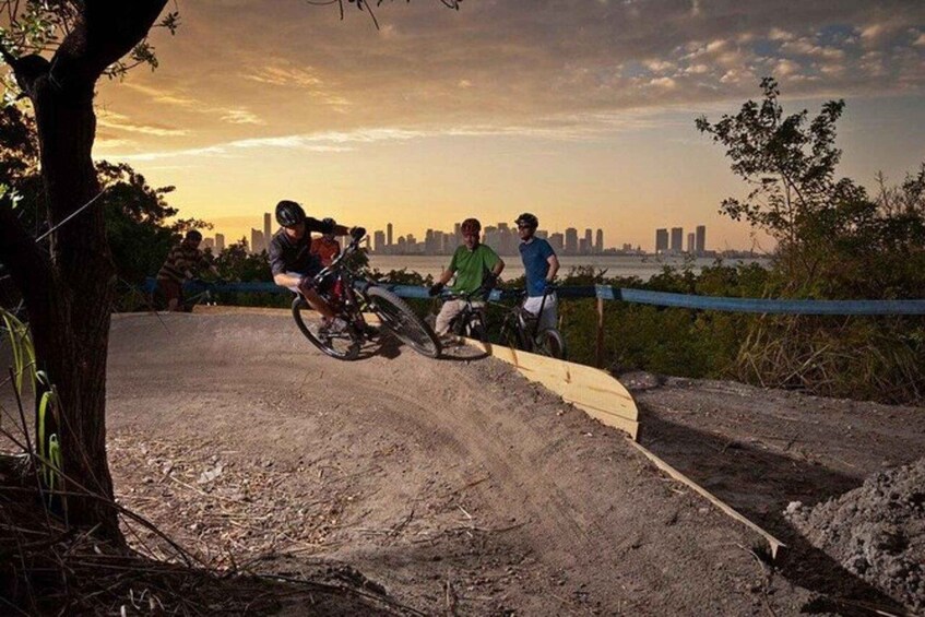 A dirt bike track with riders and a city skyline in the background. 1