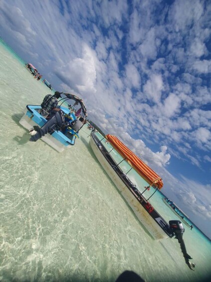 A clear turquoise sea with a boat and a striped canopy. 4