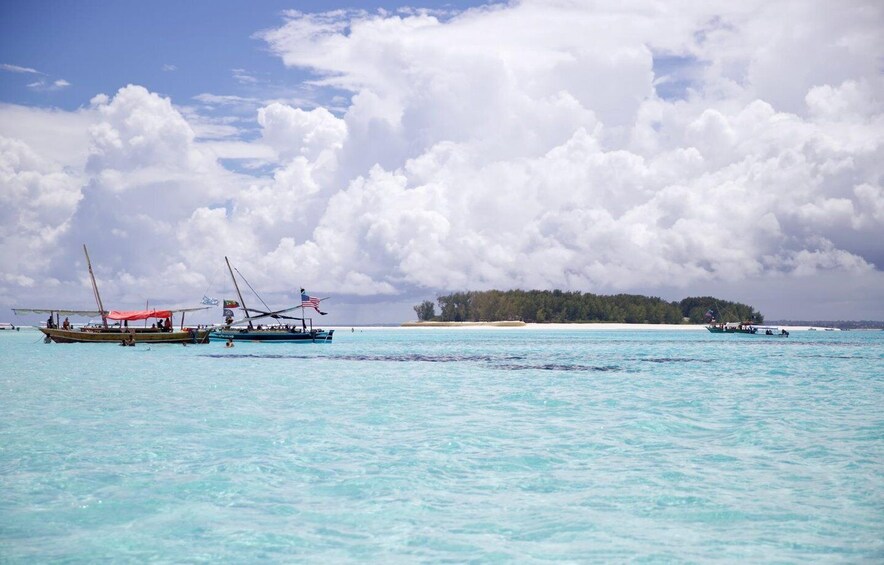 A turquoise sea with boats and a small island in the distance. 1