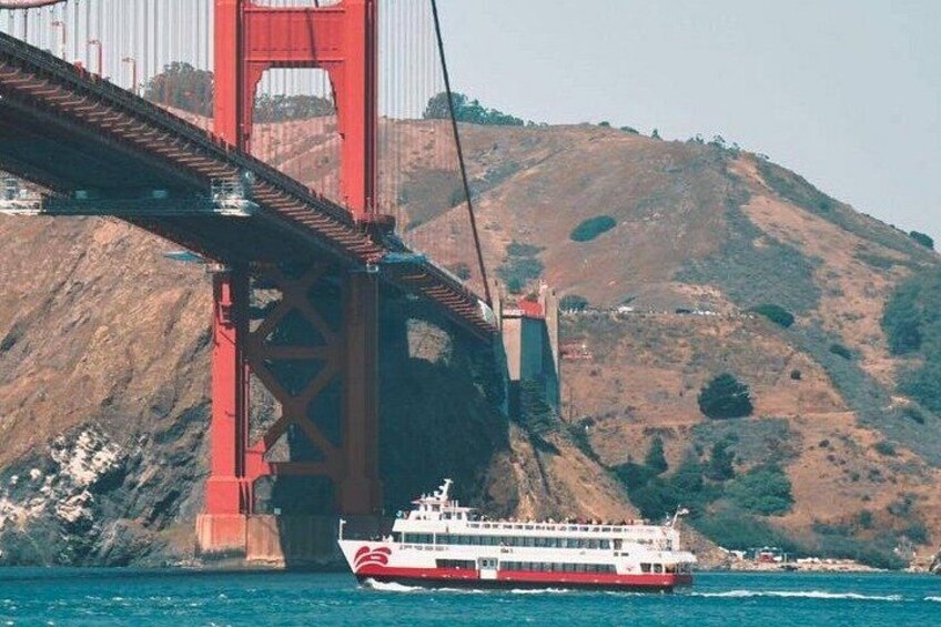 A ferry crossing the Golden Gate Bridge with a mountainous landscape in the background. 1