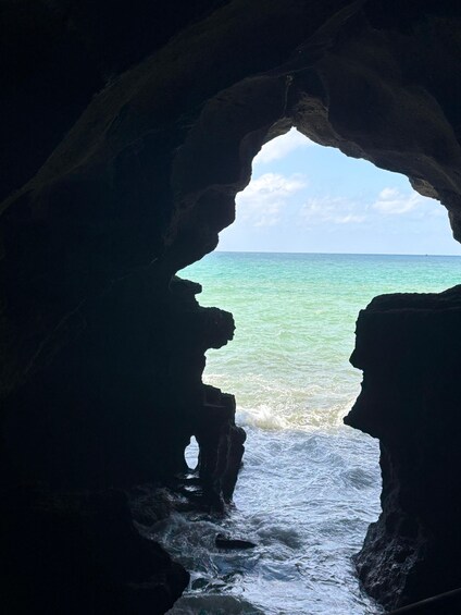 A cave opening to a turquoise sea with waves crashing against the rocks. 1
