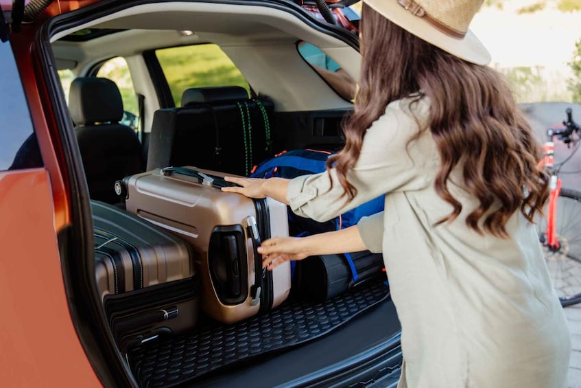 A person loading a suitcase into the trunk of a car. 2