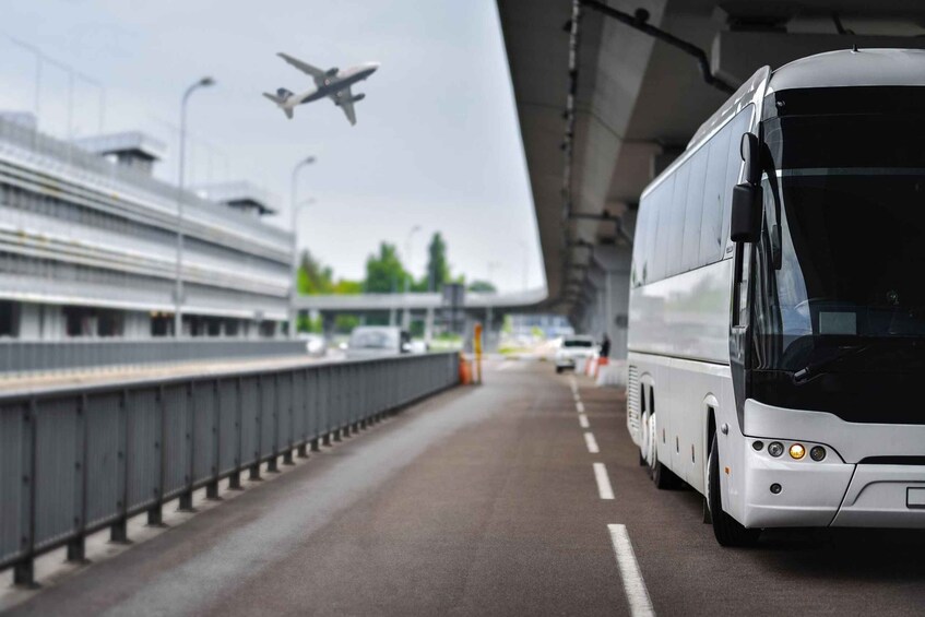 A bus on a road with an airplane flying overhead. 3