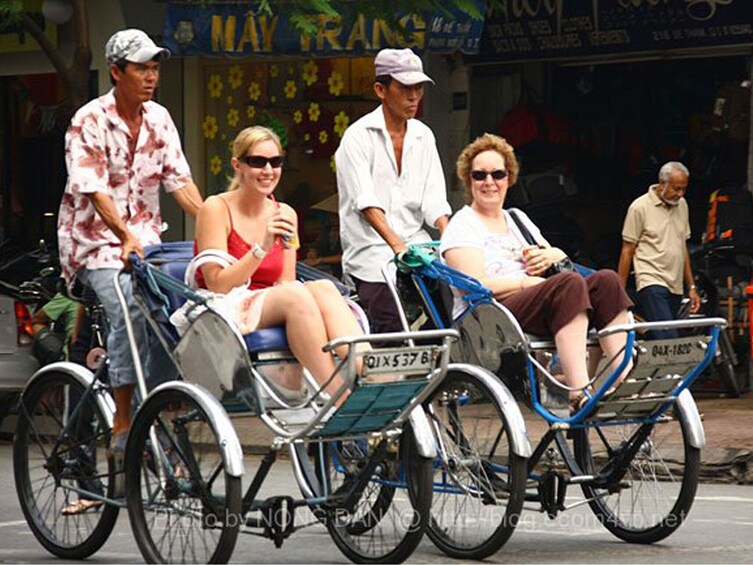 A group of people riding a tricycle with attached bicycle seats. 4