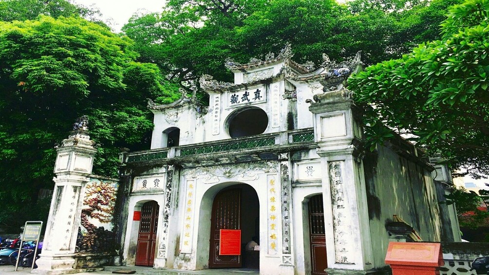 A traditional Chinese gate with ornate carvings and a red lantern hanging from the center archway. 1