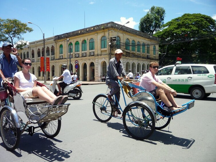 People riding rickshaws on a street with a historic building in the background. 5
