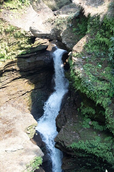 A waterfall cascading over moss-covered rocks in a forested area. 2