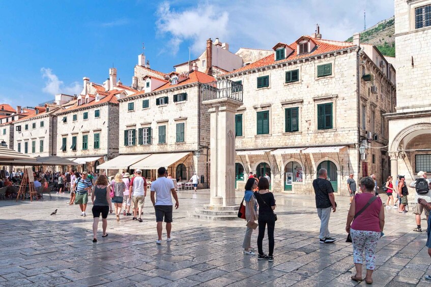 A bustling square with historic stone buildings, tourists, and outdoor seating areas. 4
