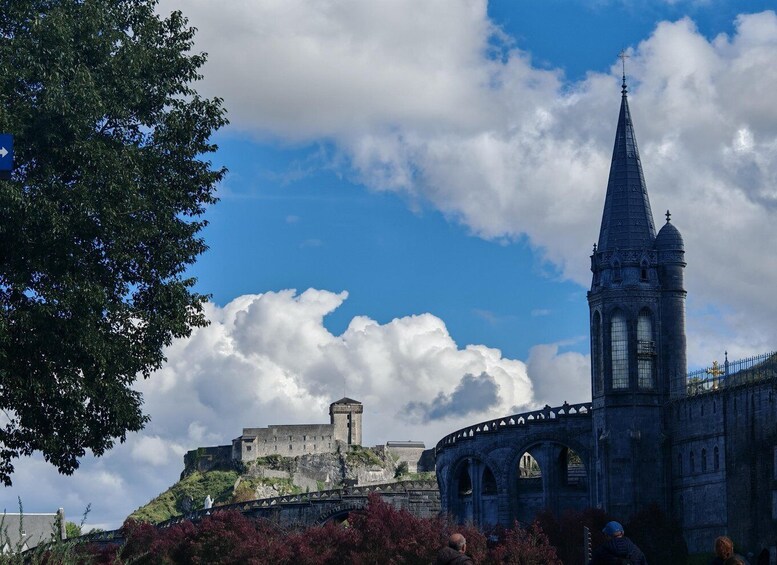 A historic castle with a tower, a stone bridge, and a church with a spire. 4