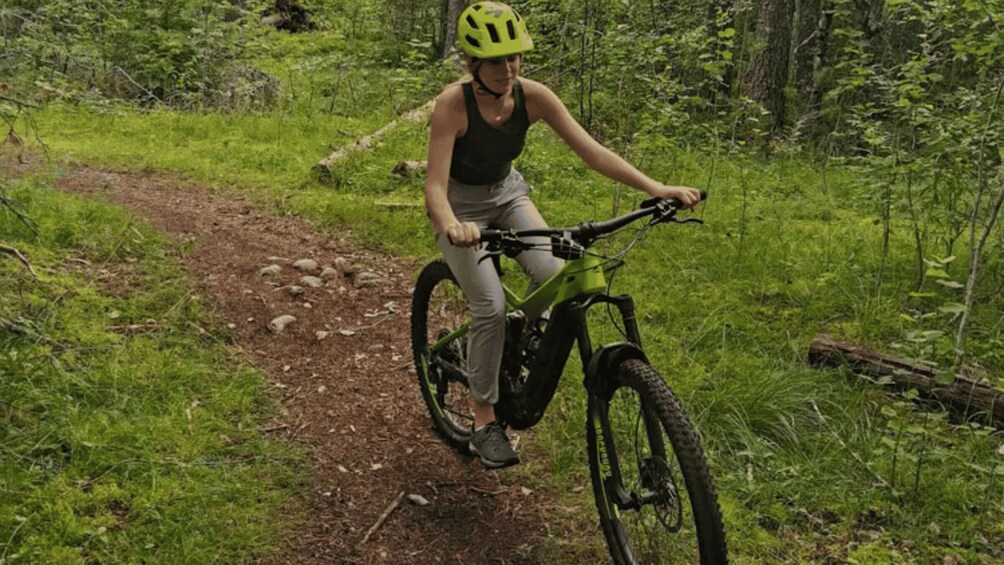A person riding a mountain bike on a dirt trail in a forested area. 1