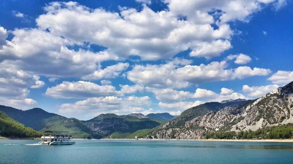 A boat on a calm lake with mountains in the background and a partly cloudy sky. 4
