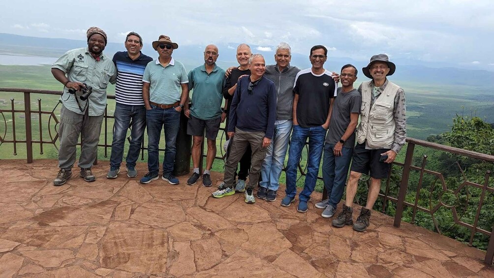 A group of people standing on a stone platform with a scenic view of a valley and mountains in the background. 1