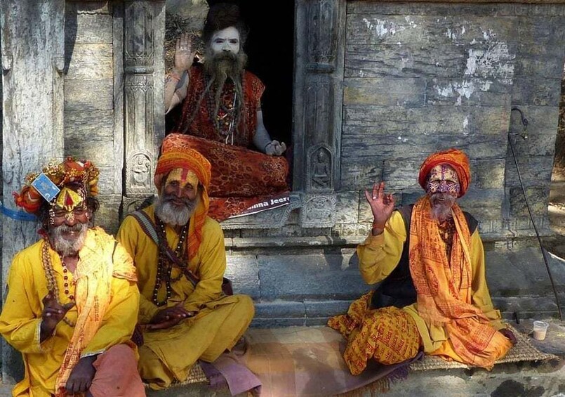 Three men in traditional attire sitting outside a temple. 1