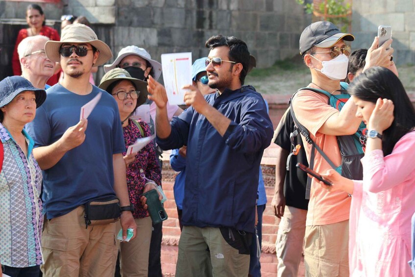 A group of people standing outdoors, some holding papers and a smartphone. 3