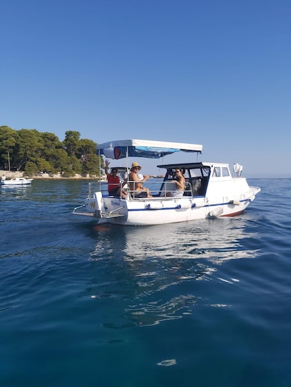 A white boat with a canopy, named 'Toma', sailing on a calm sea. 1