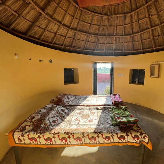 A room with a thatched roof, yellow walls, and a bed with patterned blankets. 2