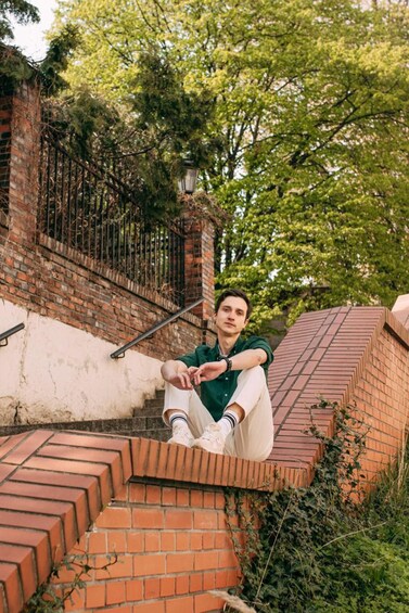 A person sitting on brick steps surrounded by greenery and a brick building. 5