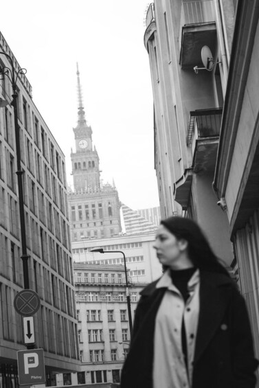 A person walking on a city street with a historic building in the background. 2