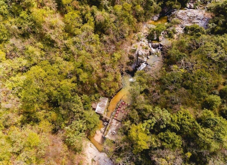 Une rivière traverse une forêt dense, parsemée d’affleurements rocheux, et une petite construction en bois se trouve près de l’eau. 2
