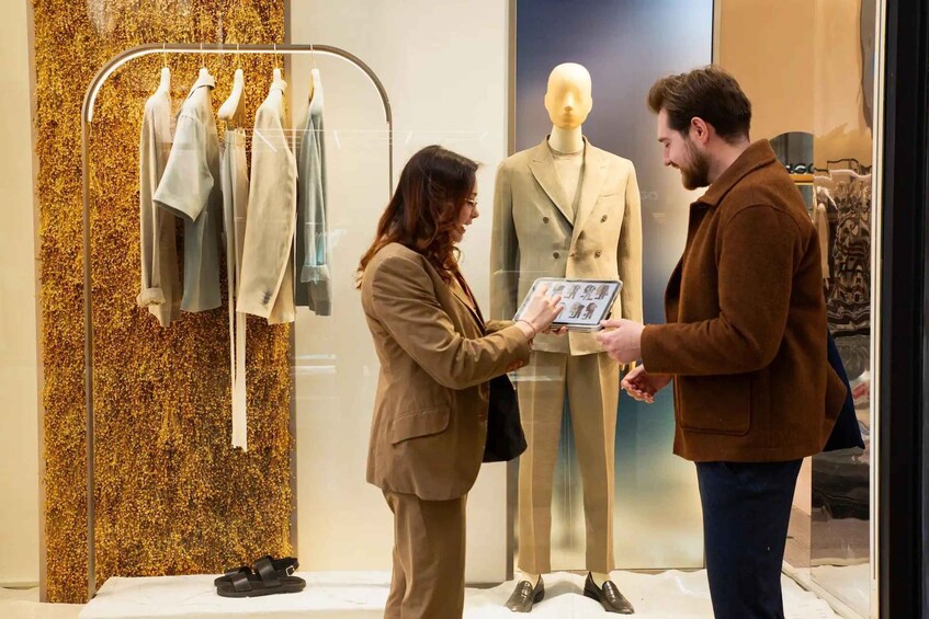 A person holding a tablet in a clothing store with mannequins and racks of clothes. 5
