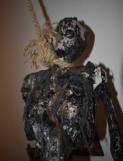 A sculpture with a rough texture and a rope tied around its neck. 5