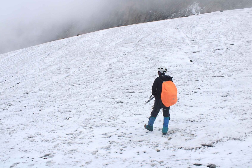 A person walking on a snowy slope with a backpack. 4