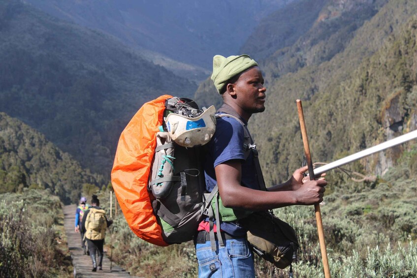 A person hiking with a large backpack and walking stick in a mountainous area. 3