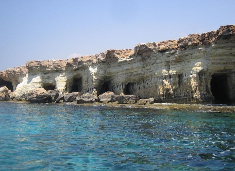 A coastal cliff with caves and clear blue water. 4