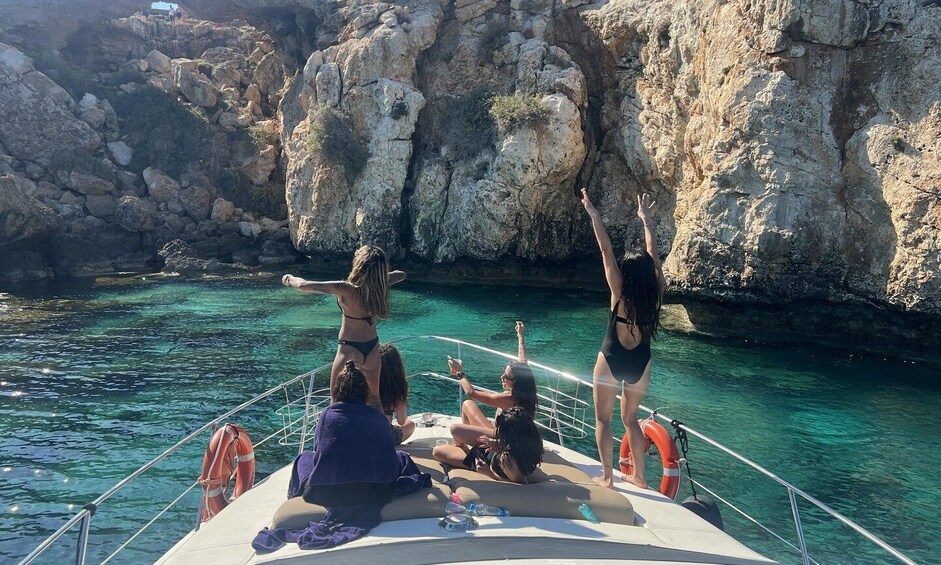 A boat with people enjoying the water and cliffs in the background. 5
