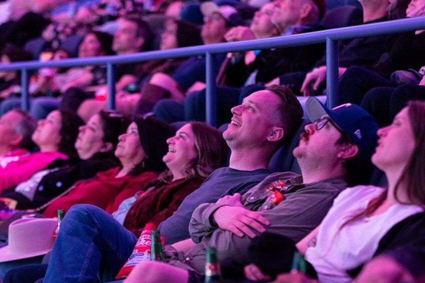 Un auditorium intérieur où des personnes sont assises en rangées, certaines tenant des boissons à la main. 2