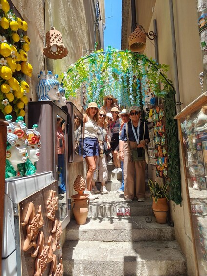 A narrow street with a group of people standing under a decorative archway. 2
