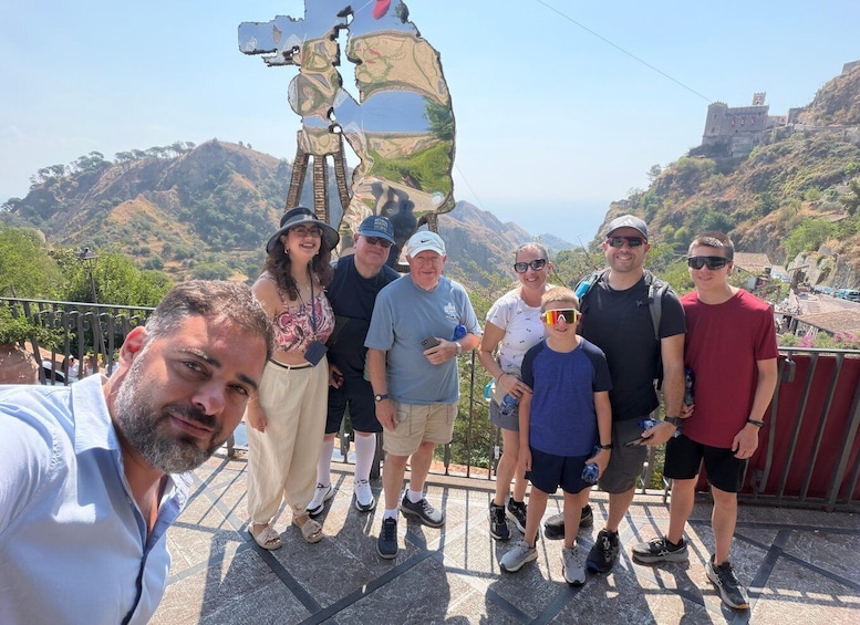 A group of people standing on a viewing platform with a scenic landscape in the background. 2