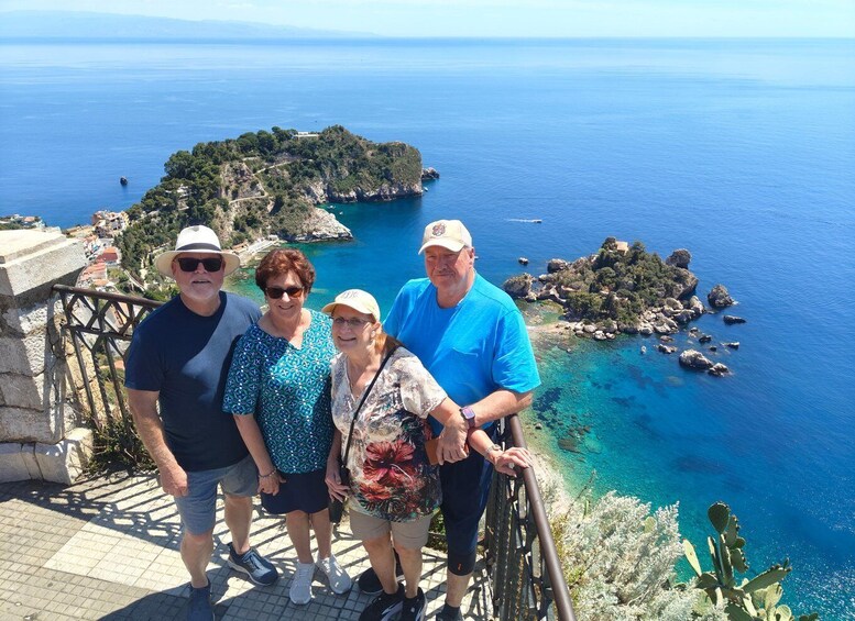 A group of people on a stone staircase overlooking a coastal landscape with clear blue waters and rocky islands. 4